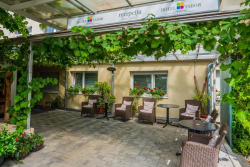a patio area with chairs, tables and umbrellas at Hotel Tabor in Maribor