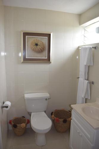a white bathroom with a toilet and a sink at Golden View Apartment in Saint James