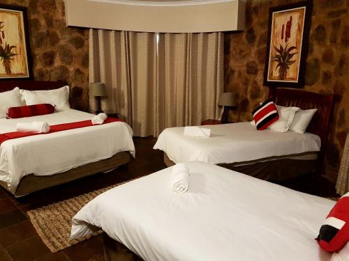 a hotel room with two beds with white sheets at Gabbata Lodge in Leeuwfontein