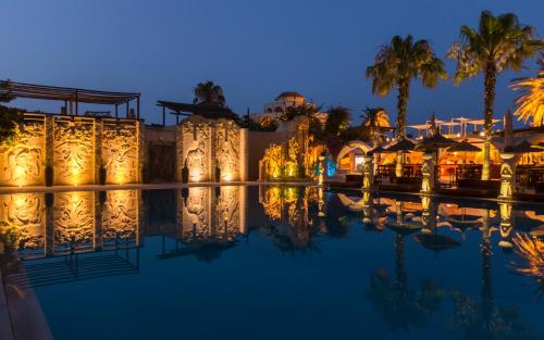 a pool at night with palm trees and lights at Africa Jade Thalasso in Korba