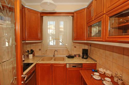 a kitchen with wooden cabinets and a sink at Giannis Apartment in Kavála