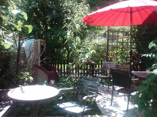 a patio with tables and chairs and a red umbrella at Ferienhaus Waldsicht in Flachau