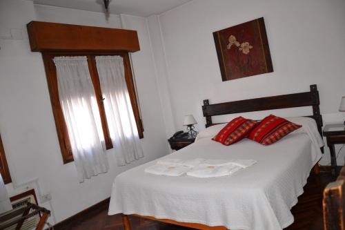 a bedroom with a white bed with red pillows at Hotel Regidor in Salta