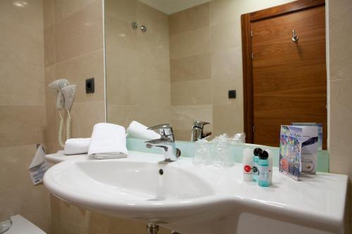 La salle de bains est pourvue d'un lavabo blanc et d'un miroir. dans l'établissement Sercotel Riscal, à Puerto Lumbreras