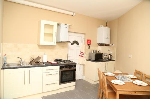 a kitchen with white cabinets and a wooden table at Birmingham Central Station Apartment (Flat 1) in Birmingham
