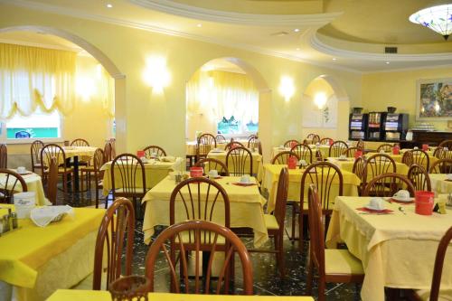 a restaurant with tables and chairs with yellow table cloth at Hotel Ettoral in Lido di Jesolo