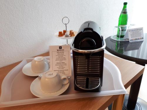 a coffee maker sitting on a table with two cups at Hotel Restaurant Clemens-August in Ascheberg