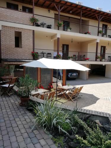 a patio with an umbrella in front of a building at Végvár Spa Apartman in Gyula