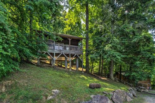 a tree house with a deck in the woods at Nantahala Cabins in Bryson City