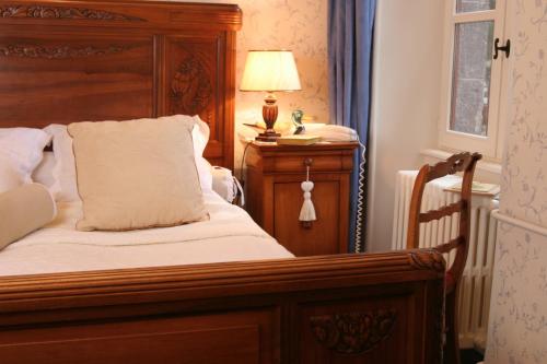 a bed with a wooden headboard and a lamp on a table at Castel Hotel 1904 in Saint-Gervais-dʼAuvergne