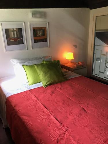 a bedroom with a red bed with two green pillows at Appartamenti I Giardini Di Villa Melzi in Bellagio