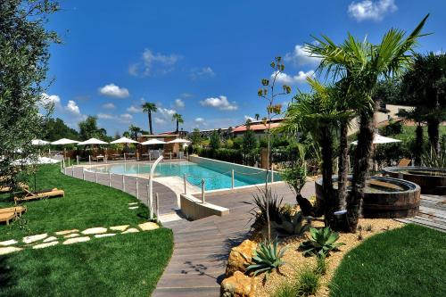 a swimming pool in a resort with trees and umbrellas at Relais Bellaria Hotel & Congressi in Bologna