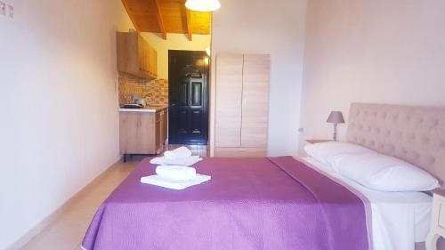 a bedroom with a purple bed with towels on it at Arianna in Paleokastritsa