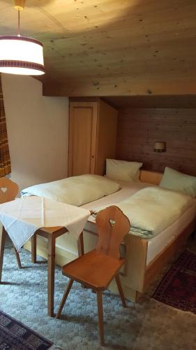 a bedroom with two beds and a chair and a table at Junser Gasthausl in Tux