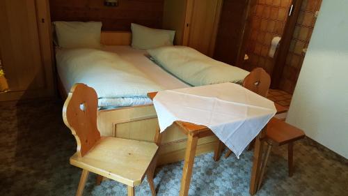 a bedroom with a bed with a chair and a table at Junser Gasthausl in Tux