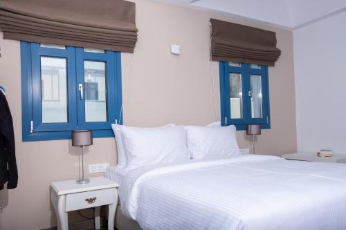 a bedroom with blue windows and a white bed at Tristhenia in Perissa