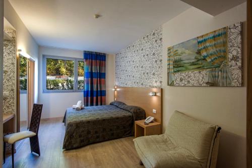 a hotel room with a bed and a chair at Relais Bellaria Hotel & Congressi in Bologna
