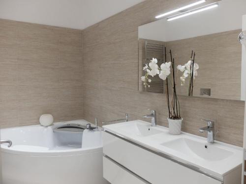 a bathroom with two sinks and a mirror and flowers at Centro Storico Suites in Ferrara