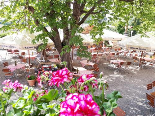 a group of tables and chairs and a tree with flowers at Hotel Linde in Günzburg