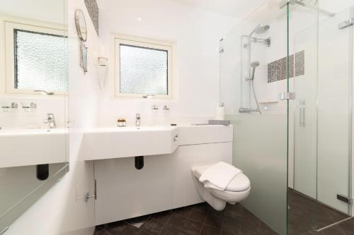 biała łazienka z 2 umywalkami i toaletą w obiekcie Sundbyholms Slott w mieście Sundby