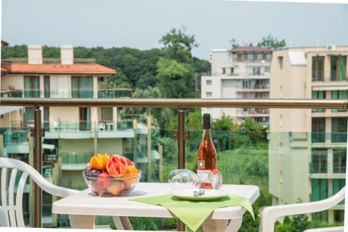 a table with a bottle of wine and a bowl of fruit at Aparthotel Hotel Prestige City II in Primorsko
