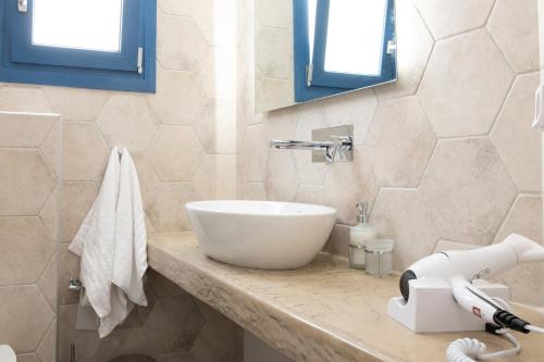 a bathroom with a white bowl sink on a counter at Tristhenia in Perissa