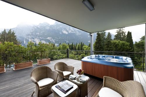 a deck with a hot tub and chairs and a table at Du Lac Et Du Parc Grand Resort in Riva del Garda