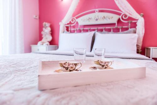 a pink bedroom with a white bed with a tray with glasses at Villa Sophia in Mitikas