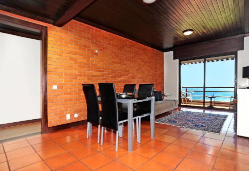 a dining room with black chairs and a brick wall at Ocean View in Estoril - Checkinhome in Estoril