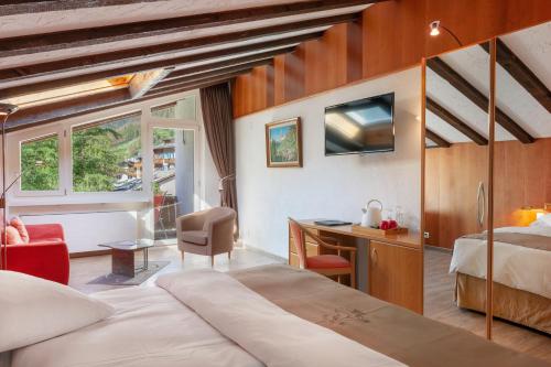 a living room with a bed and a window at Hotel Beau Rivage in Zermatt