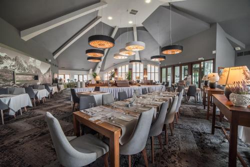 a dining room with tables and chairs and windows at Grand Nosalowy Dwór in Zakopane