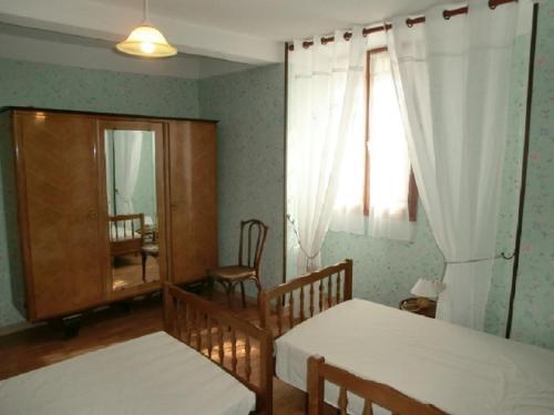 a bedroom with two beds and a window and a chair at Lou Filadour rez de chaussée 5 personnes in Jausiers