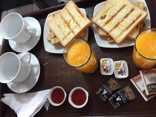 ein Tablett mit Frühstücksfutter, Toast und Orangensaft in der Unterkunft Majestuoso Hospedaje in Tacna