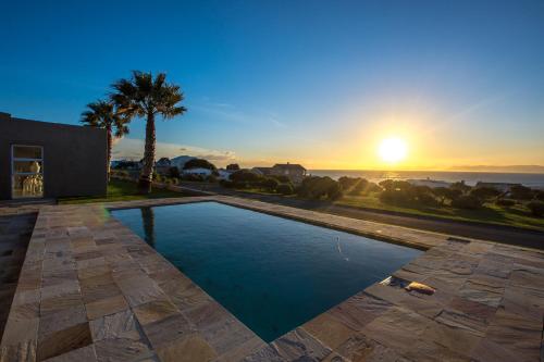 a swimming pool with the sunset in the background at Benguela in Gansbaai