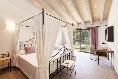 a bedroom with a canopy bed and a desk at Binibona Gran in El Port de la Selva