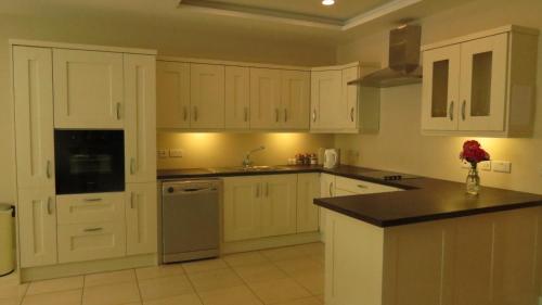 a kitchen with white cabinets and a black counter top at Rossa House in Rosscarbery
