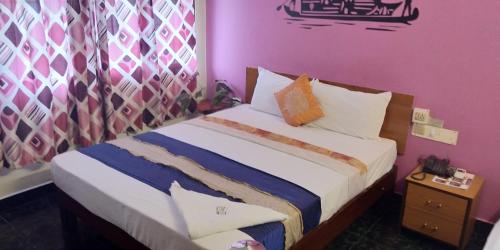 a bedroom with a bed and a purple wall at Hotel Silver Sand in Trivandrum