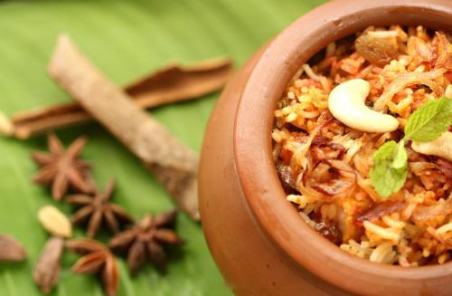 a brown bowl filled with rice and spices next to cinnamon sticks at Hotel Silver Sand in Trivandrum