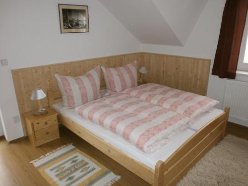 a bedroom with a wooden bed with pink and white pillows at Apartman Hrabice in Vimperk