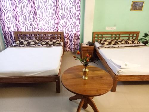 a room with two beds and a table with a vase on it at Hotel Silver Sand in Trivandrum