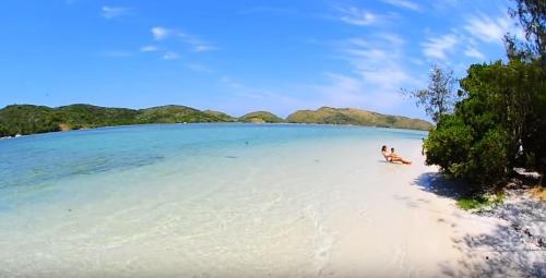 a person sitting on a beach in the water at Pousada Areia do Forte in Cabo Frio