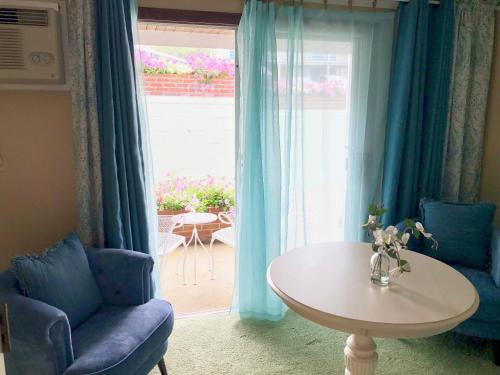 a living room with blue curtains and a table and a window at Sands Of Time Motor Inn & Harbor House in Woods Hole
