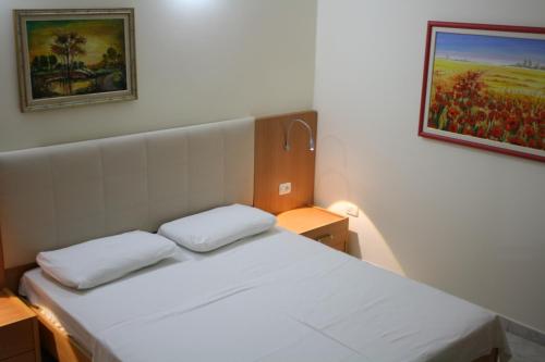a small bedroom with a white bed and a painting on the wall at Hotel Martini in Vlorë