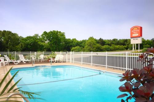 a swimming pool with a fence and chairs and a sign at Whispering Hills Inn in Branson