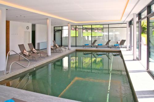 a swimming pool in a building with chairs in it at Hotel Flora in Lagundo