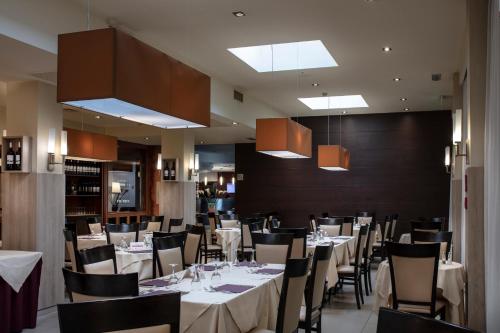 un comedor con mesas, sillas y luces en Smart Hotel Holiday, en Mestre