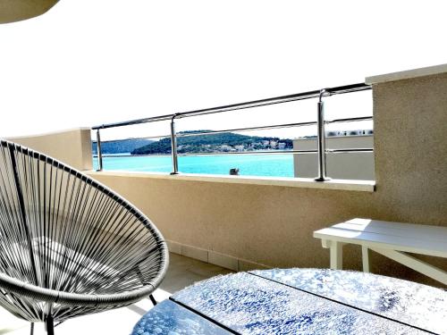 a balcony with a chair and a table and a view of the water at Maiv Apartments in Rogoznica