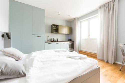- une chambre blanche avec un grand lit et une fenêtre dans l'établissement Sunny Riverside Apartments, à Prague
