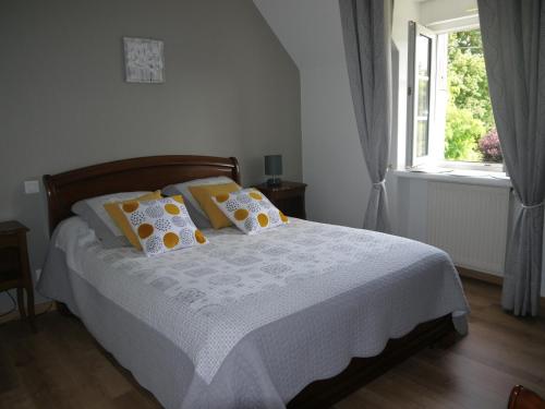 Un dormitorio con una cama con almohadas amarillas y una ventana en Chambres d'Hotes Les Sageais en Baguer-Morvan
