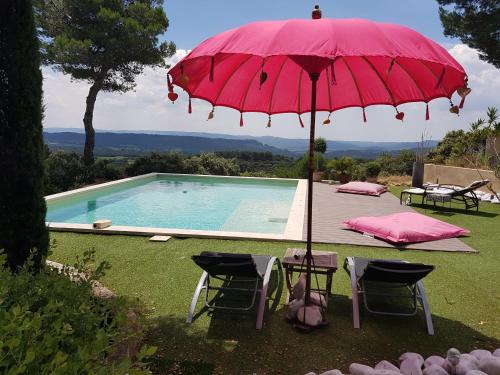 a red umbrella and two chairs and a swimming pool at La Maison de Charlie in Vaugines